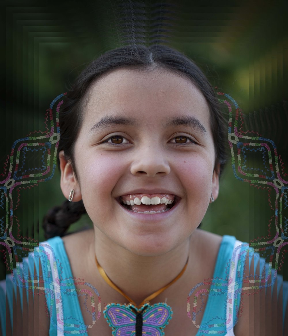 A nine year old girl looks into the camera. The border of the image has been digitally modified with traditional embroidery added