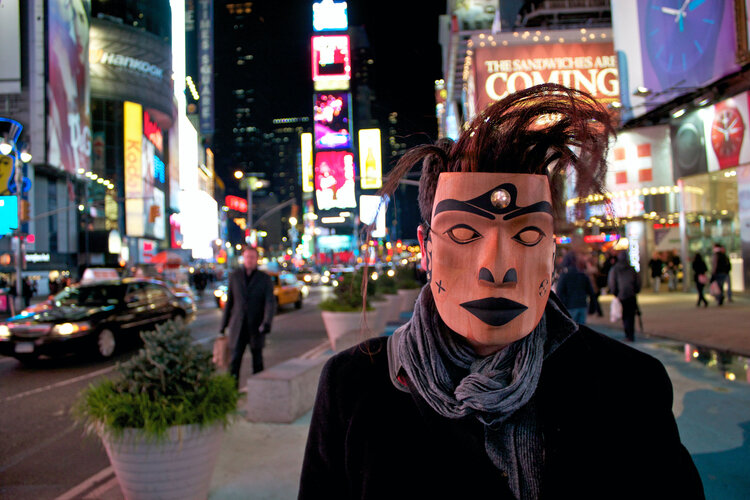 A man wears a Kwak’waka’wakw style portrait mask in the middle of Times Square in New York City.